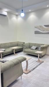 a living room with green couches and a rug at شقق مفروشة الباحة in Al Baha