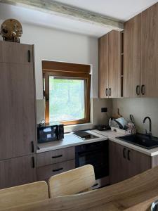 a kitchen with wooden cabinets and a window in it at Zelena dolina Zminica in Zminica +19 photos