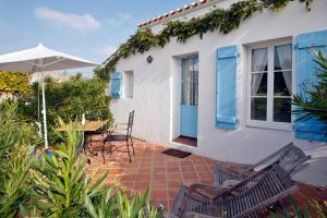 a house with a patio with chairs and an umbrella at Blanc Marine in Noirmoutier-en-l'lle