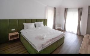 a bedroom with a large bed with a green headboard at Hanul Pelerinului Cepari in Cepari Ungureni
