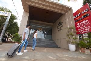 a man and woman walking outside of a building with a suitcase at Clickon Value Seven Hills in Chik Bānavar