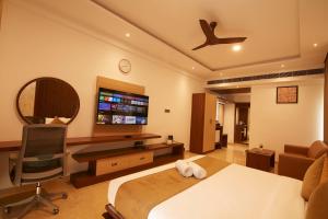 a bedroom with a bed and a desk and a tv at Clickon Value Seven Hills in Chik Bānavar