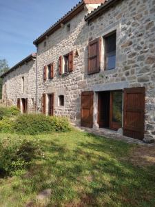 an old stone house with wooden doors and a yard at Chambre d'hôte lozérienne in Saint-Privat-du-Fau