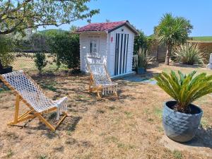 two wooden chairs sitting in front of a small house at Cabane romantique climatisée avec piscine en pleine nature in Montignac