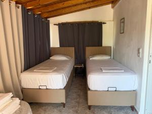 two beds in a room with black curtains at Harry's House in Elafonisos