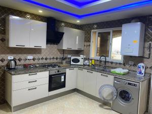 a kitchen with white cabinets and a blue ceiling at Perle de Soliman Plage in Soliman