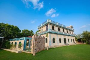 an old house with a blue roof on a grass field at Sambhariya Bagh Resort in Kānota