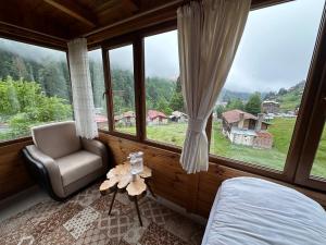 a bedroom with a bed and a chair and large windows at Ayder Serender Otel in Çamlıhemşin