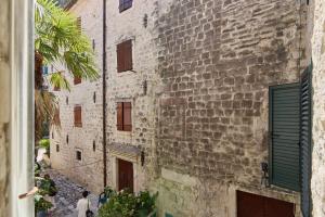 an alley in an old stone building with green shutters at Modern Studio Old Town by MN Property in Kotor