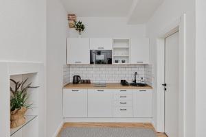 a white kitchen with white cabinets and a sink at Modern Studio Old Town by MN Property in Kotor