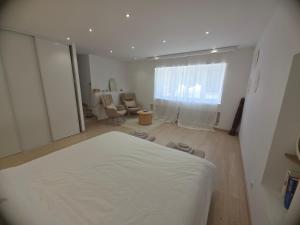 ein Schlafzimmer mit einem weißen Bett und ein Wohnzimmer in der Unterkunft Vertu'Ose avec jacuzzi in Morbier