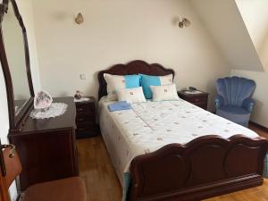 a bedroom with a large bed and a blue chair at SERRA e MAR in Murtais