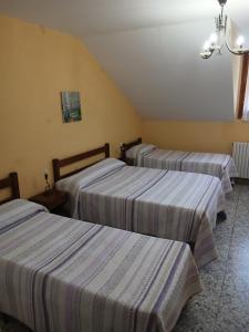 three beds in a hotel room with striped sheets at El Chate in Sarvisé +88 photos