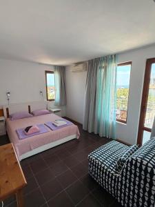 a bedroom with two beds and a table and window at Guest House Karavida in Sinemorets