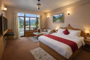a hotel room with a bed and a large window at Hotel Hollywood Vibes #riverview #premium rooms #prime location #most awarded #parking #top rated #open terrace #lawn #best selling hotel in manali in Manāli