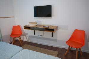 a bedroom with two red chairs and a desk with a tv at Casa Ferreira in Olaia