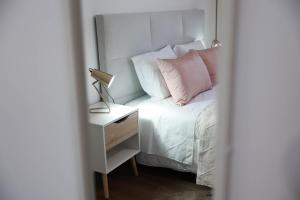 a white bed with pink pillows and a lamp on a night stand at Casa Ferreira in Olaia