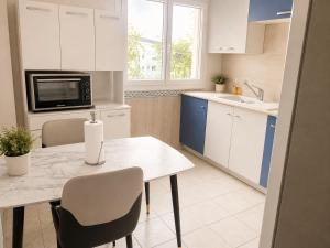 a kitchen with white cabinets and a table with chairs at Prestige appart in Chalon-sur-Saône