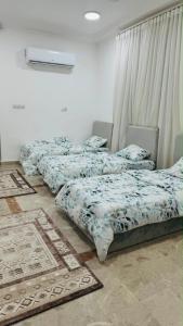 three beds in a room with rugs on the floor at فيلا in Salalah