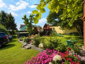 a garden with pink flowers and a playground at Magnat Dźwirzyno in Dźwirzyno