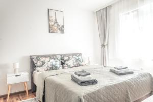 a white bedroom with a bed with towels on it at Nora Apartments in Jagodina