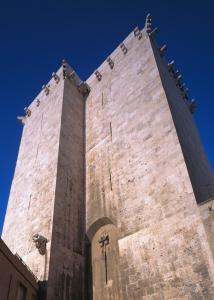 a tall brick tower with a cross on it at Sotto la torre Apartment in Cagliari