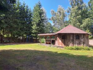 a wooden building with a playground in a field at Mazurska Chatka Pilchy in Pilchy