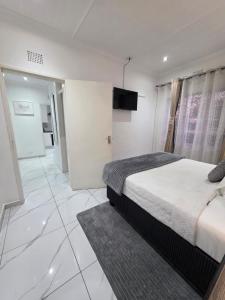 a bedroom with a bed and a television on the wall at Flourish Haven Escape in Germiston +18 photos