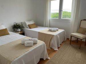 a room with two beds and a chair and a window at Villa Miramar Vistas espectaculares in Es Mercadal +11 photos