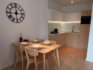 a dining room table with chairs and a clock on the wall at Apartamenty Marco Polo in Dziwnówek