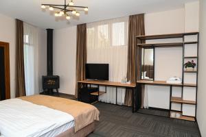 una camera da letto con un letto, una scrivania e una televisione di Rubin Hotel a Goris