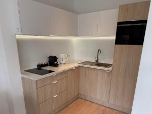 a small kitchen with white cabinets and a sink at Apartamenty Marco Polo in Dziwnówek