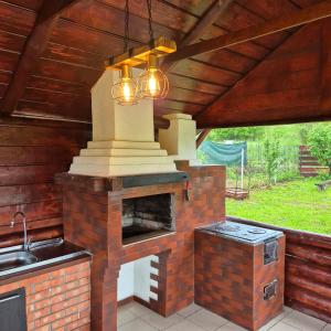 an outdoor kitchen with a brick fireplace and a sink at Casă Bubu in Cacica