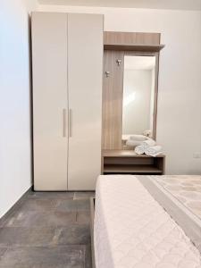 a bedroom with a large white bed and a mirror at Orchidea Apartments in Sorso