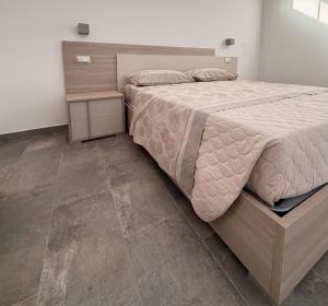 a bedroom with a large bed with a wooden headboard at Orchidea Apartments in Sorso