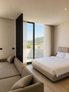a bedroom with a bed and a couch and a window at Emera Apartments in Vlorë