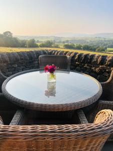 a glass table with a vase of flowers on it at Heigh Farmhouse in Lancaster