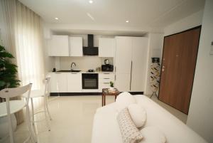 a living room with a white couch and a kitchen at The Calm Coast Studio in Harqalah