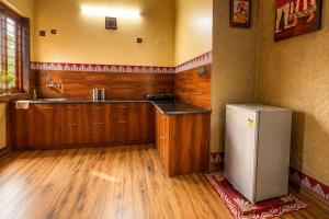 a kitchen with wooden cabinets and a refrigerator at Ramashray - Mud House Living in Haldwāni