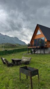 a log cabin with a table and benches in a field at Lunara Chalet in Kazbegi