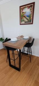 a wooden table with two chairs and a painting on the wall at Cosy Haven - Large Comfy Dwelling in Mandurah