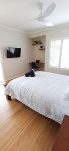 a bedroom with a white bed and a desk at Cosy Haven - Large Comfy Dwelling in Mandurah