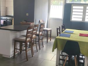 a kitchen with a bar with chairs and a table at Gite, Route Des Laves in Saint-Philippe