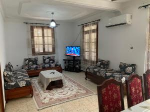 a living room with couches and a tv at Chez NAIM in Tichi