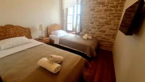 a bedroom with two beds and a brick wall at 4 Rooms in Gjirokastër