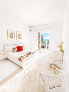 a white bedroom with a bed and a chair at Cocoon Signature in Flic-en-Flac