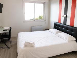 a bedroom with a large white bed and a window at Hotel Le Rohu Vannes in Séné +8 photos