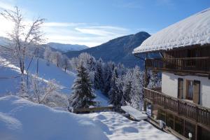 a building covered in snow with mountains in the background at Le Moulin de Bisanne in Villard-sur-Doron