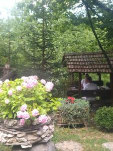 two people sitting on a bench in a garden with flowers at Cabin 3 Hill Station in Sarajevo