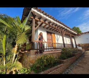 a woman standing on the balcony of a house at Cabaña Los Colibries in Barichara